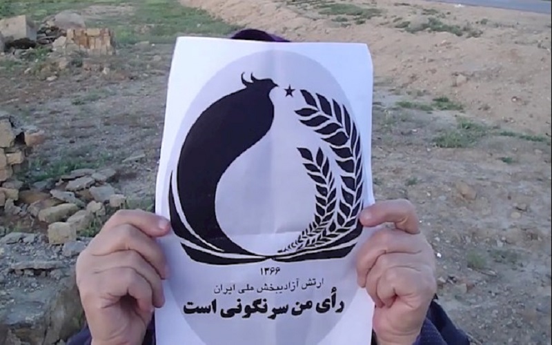 An Iranian holding a paper with the script, ‘my vote is the overthrow’