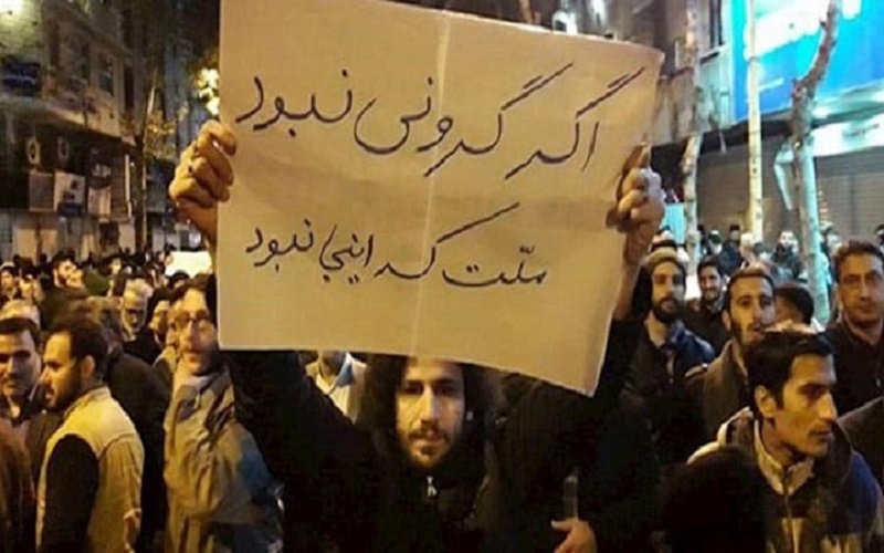 A picture of a protest by the Iranian people. The man holds a banner that says, “If things were not so expensive, the people wouldn’t be here.”