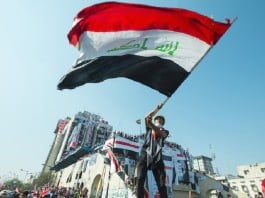 An Iraqi protester holds a flag during the October Revolution, 2019