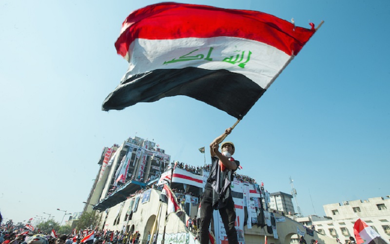An Iraqi protester holds a flag during the October Revolution, 2019